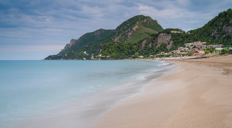 schönste Strände Griechenland: Der lange Glyfada Beach auf Korfu bietet alles was man sich wünscht: einen schönen Strand, blaues Meer und Restauration umgeben von Traumkulisse