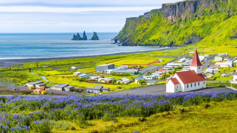 Dorf und Reynisfjara Strand mit Basaltfelsen, Island